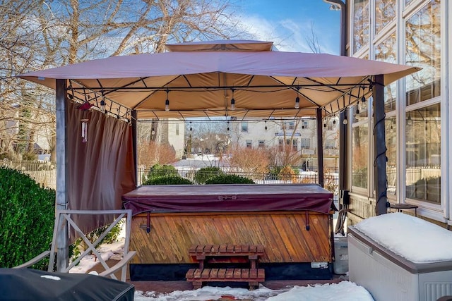 snow covered patio with a gazebo, a hot tub, and a grill