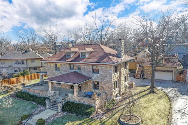 traditional style home with a chimney, concrete driveway, a front yard, a patio area, and fence