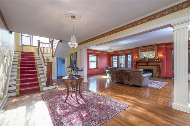 interior space with hardwood / wood-style flooring, crown molding, decorative columns, and a notable chandelier