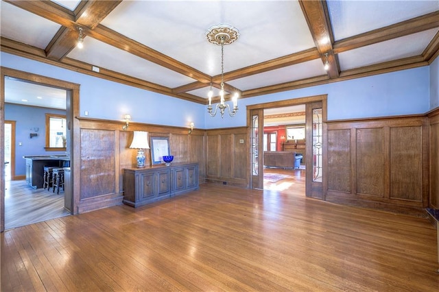 interior space featuring an inviting chandelier, beamed ceiling, coffered ceiling, and light wood-type flooring