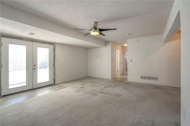 carpeted empty room with ceiling fan, french doors, and a textured ceiling