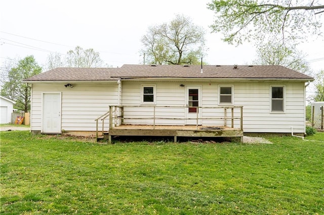 back of house with a shingled roof, a wooden deck, and a yard