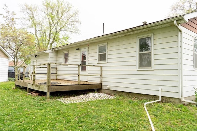 rear view of property featuring a yard and a wooden deck