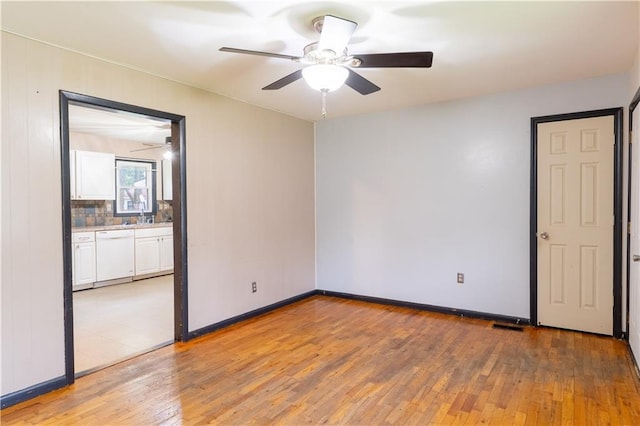 spare room with a ceiling fan, visible vents, a sink, baseboards, and light wood-style floors