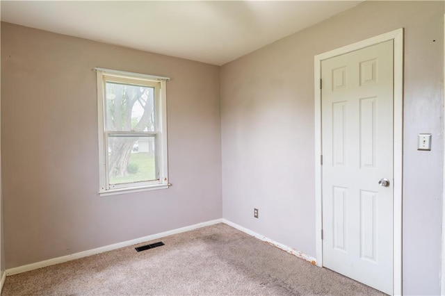 unfurnished room with visible vents, carpet, and baseboards