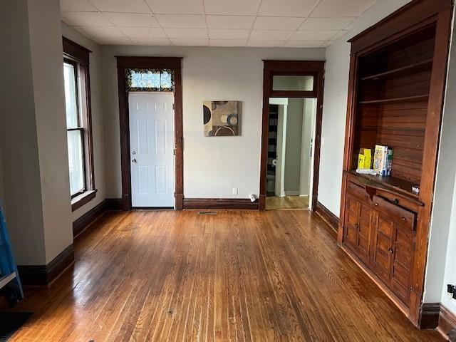 interior space with a paneled ceiling and dark hardwood / wood-style flooring