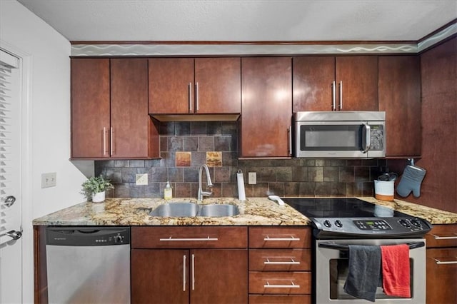 kitchen featuring light stone countertops, decorative backsplash, appliances with stainless steel finishes, and sink