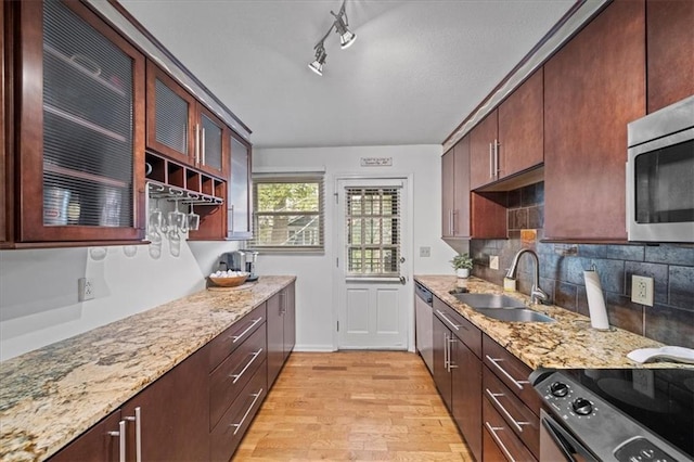 kitchen featuring light stone countertops, appliances with stainless steel finishes, tasteful backsplash, sink, and light wood-type flooring