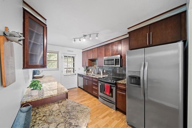 kitchen with light wood-type flooring, appliances with stainless steel finishes, sink, and light stone countertops