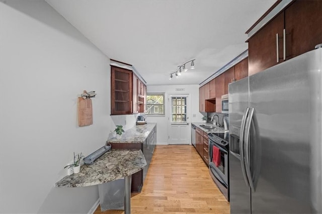 kitchen with light stone countertops, appliances with stainless steel finishes, light hardwood / wood-style floors, and sink