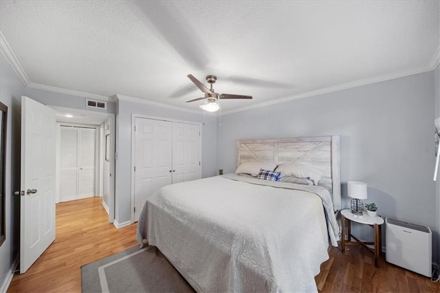 bedroom featuring a textured ceiling, wood-type flooring, a closet, ceiling fan, and crown molding