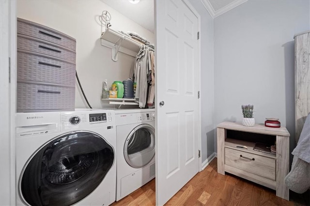 laundry area with hardwood / wood-style floors, washer and clothes dryer, and ornamental molding