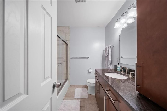 bathroom featuring toilet, tile patterned floors, an enclosed shower, and vanity