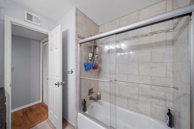 bathroom featuring hardwood / wood-style flooring and bath / shower combo with glass door