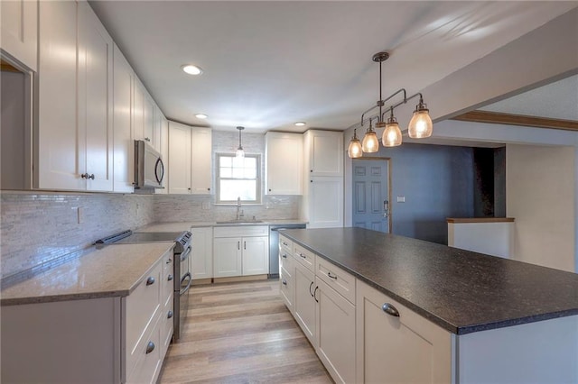 kitchen featuring hanging light fixtures, white cabinetry, and stainless steel appliances