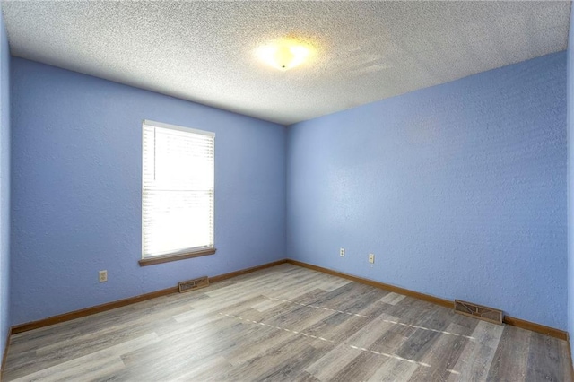 unfurnished room featuring a textured ceiling and hardwood / wood-style floors