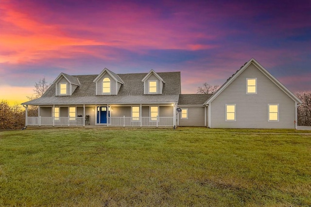 cape cod house with a yard and covered porch