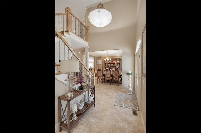 tiled entryway with a towering ceiling and an inviting chandelier