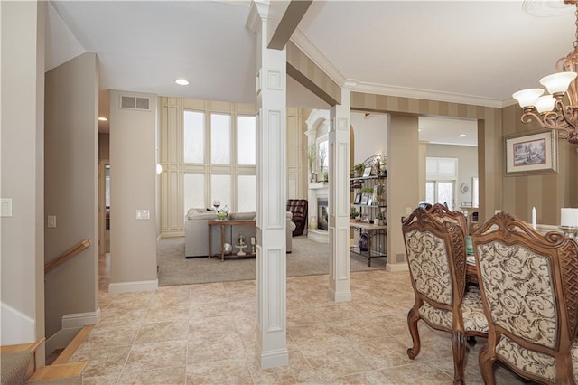 dining area featuring decorative columns, crown molding, a notable chandelier, and light colored carpet