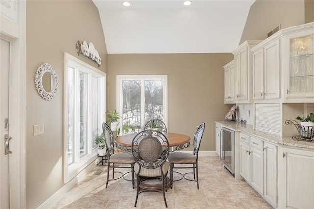 dining space with lofted ceiling, light tile patterned flooring, and wine cooler