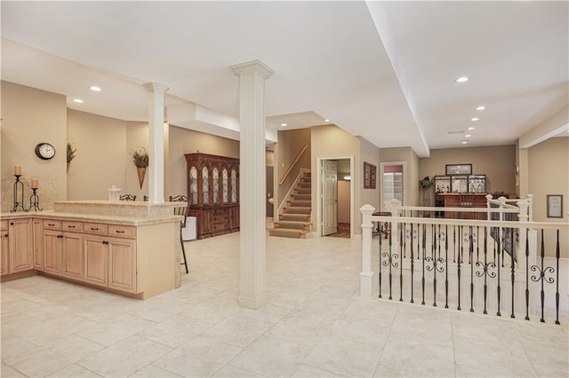 interior space with light brown cabinetry, kitchen peninsula, and ornate columns