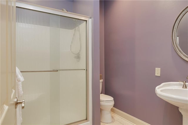 bathroom featuring toilet, tile patterned flooring, and a shower with shower door