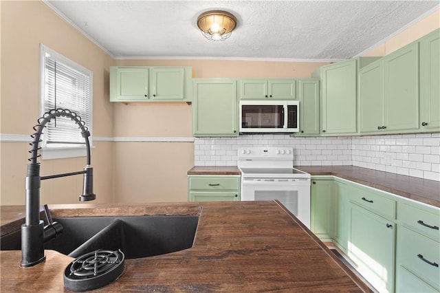 kitchen with white appliances, wooden counters, green cabinets, sink, and backsplash