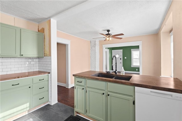 kitchen with sink, green cabinetry, tasteful backsplash, white dishwasher, and wooden counters