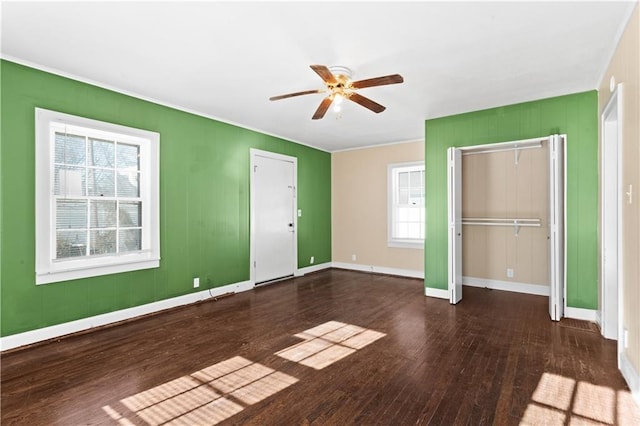 unfurnished bedroom featuring two closets, ceiling fan, dark hardwood / wood-style floors, and multiple windows