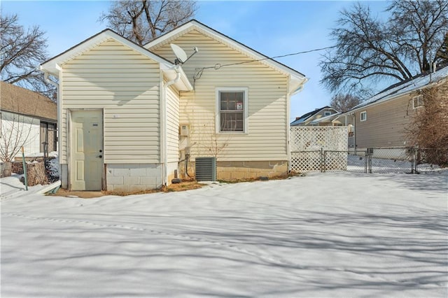 snow covered rear of property featuring central AC unit