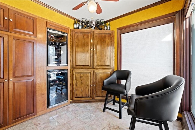 sitting room featuring ceiling fan, indoor bar, ornamental molding, and beverage cooler