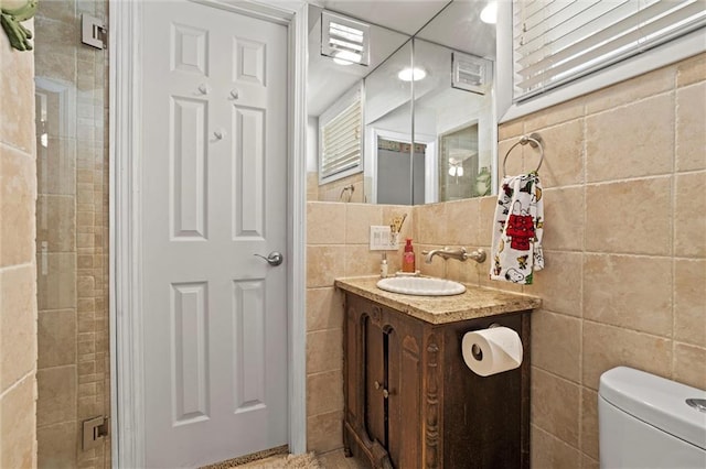 bathroom featuring vanity, toilet, and tile walls