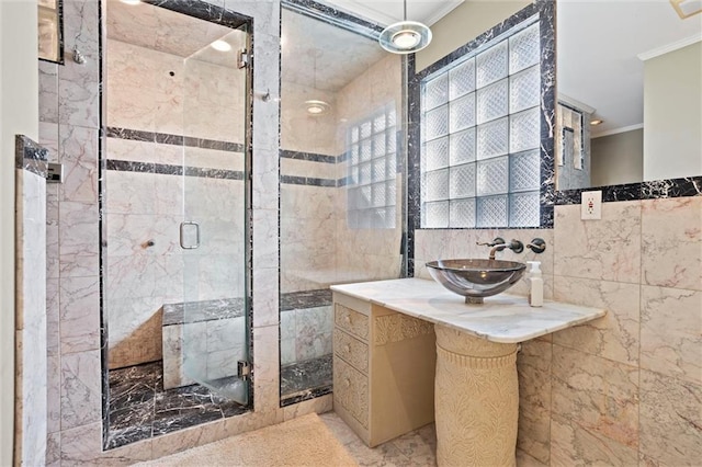 bathroom with crown molding, a shower with shower door, sink, and tile walls