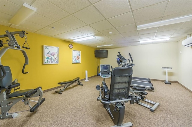 workout area featuring a wall unit AC, carpet flooring, and a drop ceiling