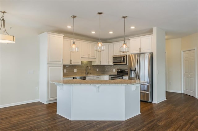 kitchen with light stone counters, stainless steel appliances, white cabinets, and hanging light fixtures