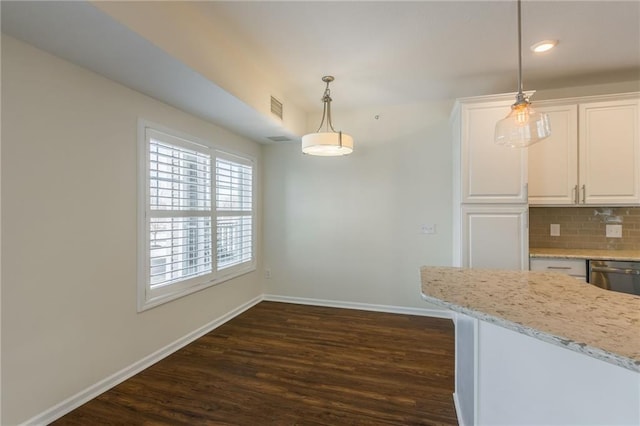 kitchen with backsplash, decorative light fixtures, light stone countertops, stainless steel dishwasher, and white cabinets