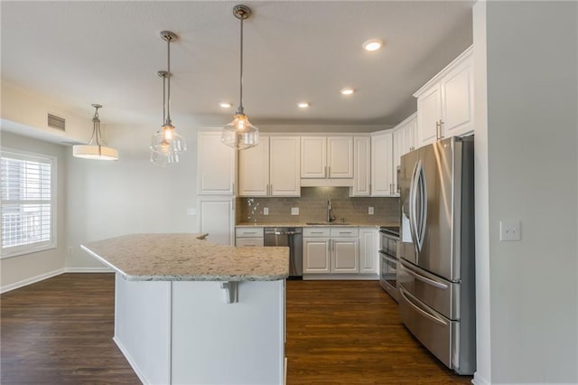 kitchen featuring pendant lighting, white cabinetry, stainless steel appliances, sink, and backsplash