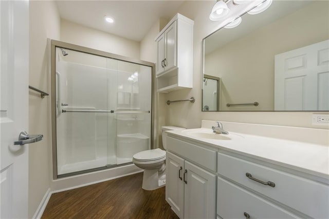 bathroom with vanity, toilet, hardwood / wood-style floors, and a shower with door