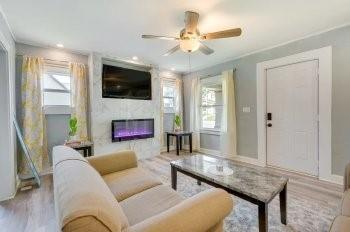 living room with ceiling fan, light hardwood / wood-style flooring, ornamental molding, and a fireplace