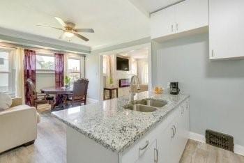 kitchen with light stone countertops, white cabinetry, kitchen peninsula, and sink