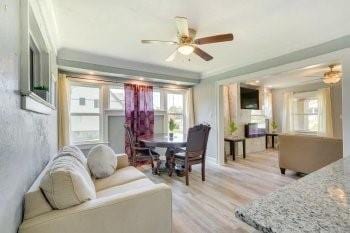 living room with ceiling fan, crown molding, and light wood-type flooring