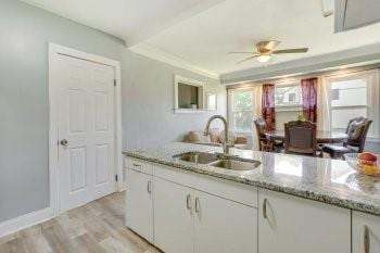 kitchen with light stone countertops, sink, white cabinetry, and ceiling fan