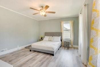 bedroom featuring ceiling fan, ornamental molding, and light wood-type flooring