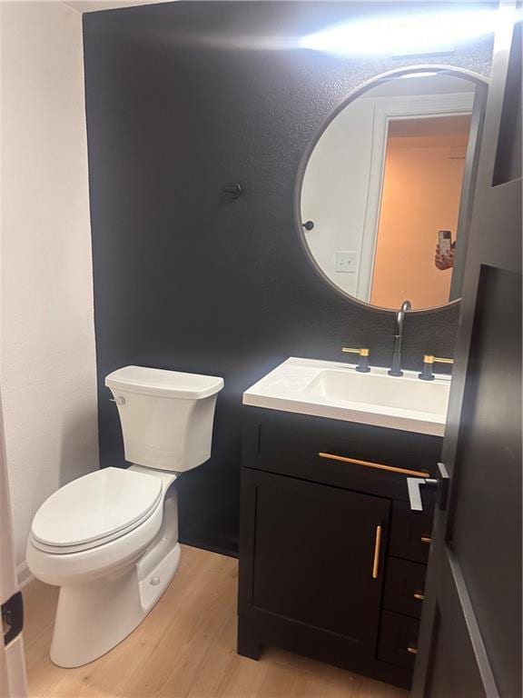 bathroom with toilet, vanity, and hardwood / wood-style floors