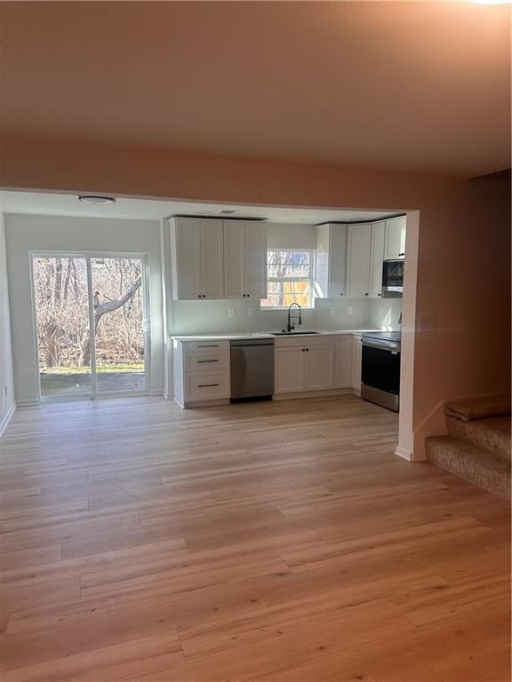 kitchen featuring range, dishwasher, light hardwood / wood-style flooring, and white cabinetry