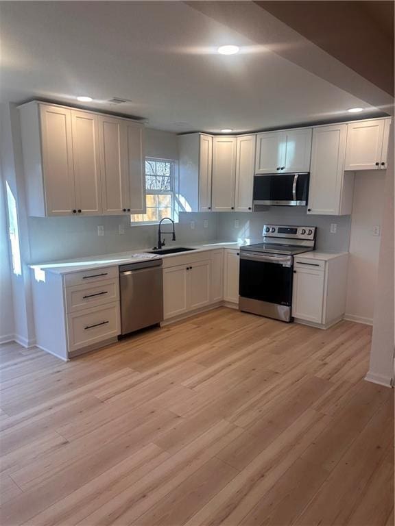 kitchen featuring sink, stainless steel appliances, light hardwood / wood-style flooring, and white cabinets