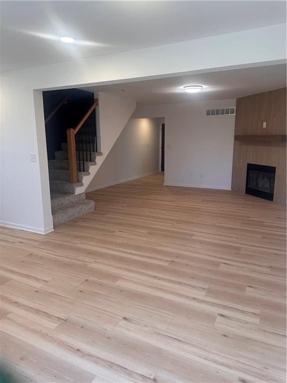 basement with a large fireplace and light wood-type flooring