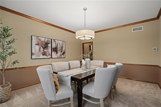 dining space with ornamental molding and light carpet