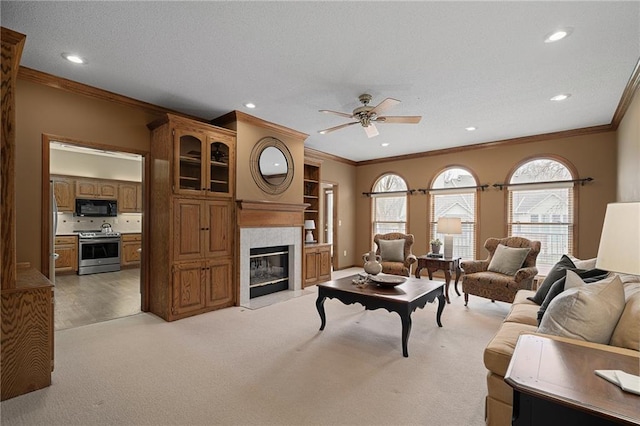 living room with light carpet, crown molding, a tile fireplace, and ceiling fan