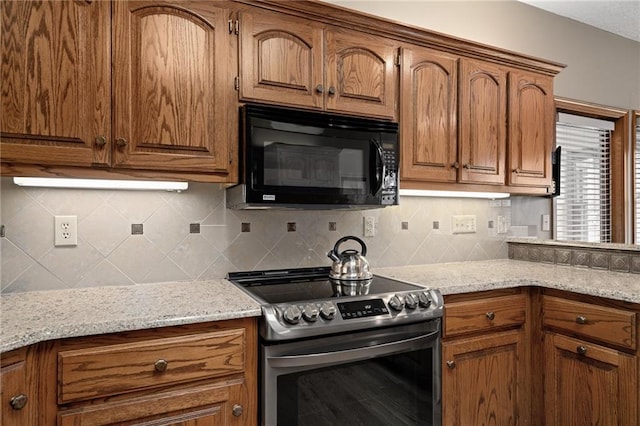 kitchen with stainless steel electric stove, backsplash, and light stone counters